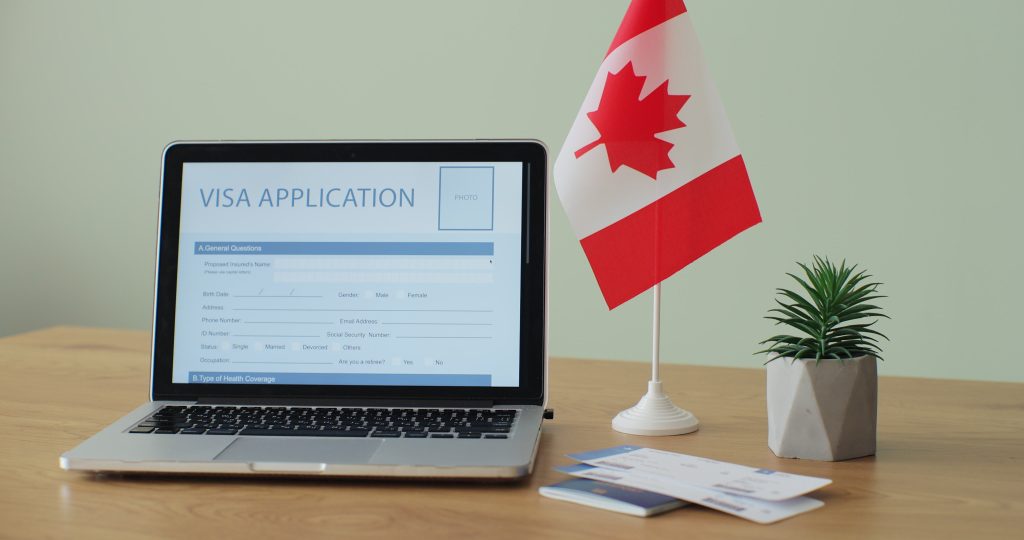 Online Canada Visa Application showing on a laptop computer screen sitting on a desk. 